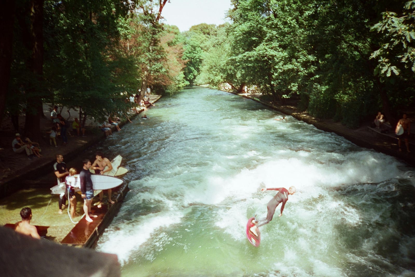 Surfers riding the Eisbach wave in Munich's English Garden